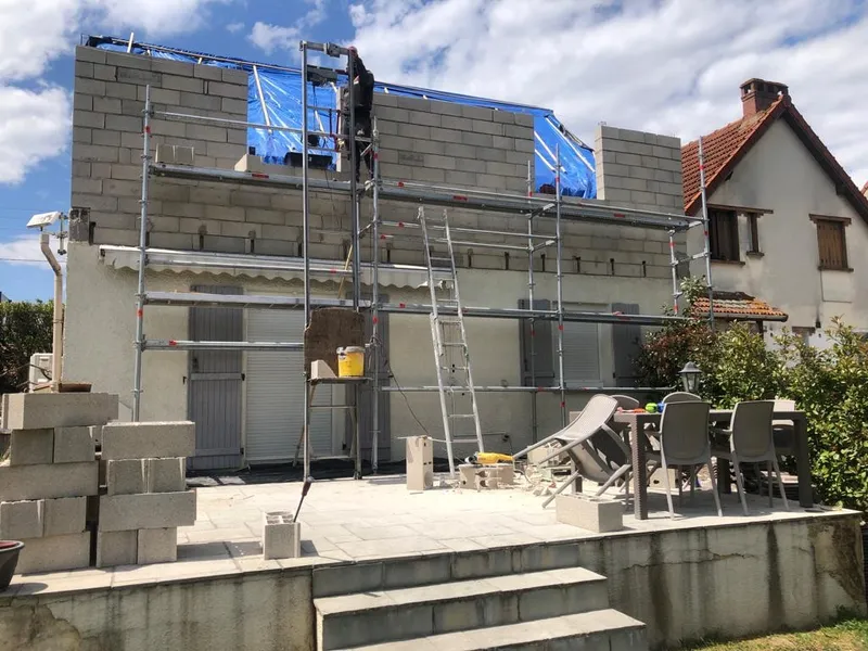 M. Rousseau montant un mur en parpaings sur un chantier dans l'Essonne