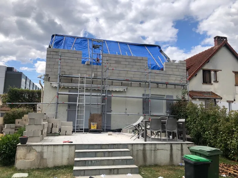 Surélévation de maison en cours dans l'Essonne, murs en parpaings sous bâche